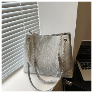 Detail of grey pleated tote bag with embossed fashion text and golden chain handle