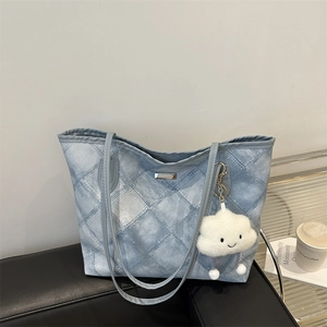 Light blue denim tote bag with white quilted pattern and cute cloud charm on sofa