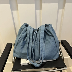 Large blue denim drawstring bucket bag with multiple pockets and shoulder strap
