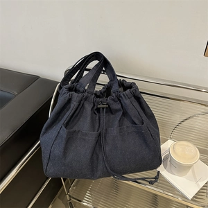 Large dark blue denim bucket bag with drawstring closure and dual front pockets