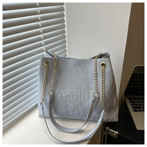 Detail of grey textured tote bag with embossed FASHION text and gold chain strap