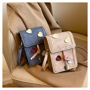 Detail of mini crossbody bags with heart stitching in denim blue and cream colors