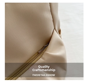 Détail de la poche zippée en métal et texture toile sur le sac fourre-tout beige