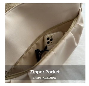 Détail de la poche intérieure zippée en toile beige montrant l'espace de rangement