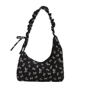 Black hobo bag with white bow prints and ruched strap on a white background