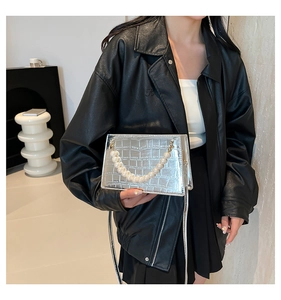 Detail of silver crocodile pattern crossbody bag with decorative pearl handle strap
