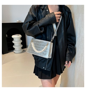 Detail of silver crocodile pattern crossbody bag with decorative large pearl handle