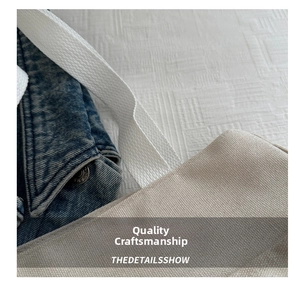 Detail of dark blue denim and beige canvas tote with white cotton webbing handles