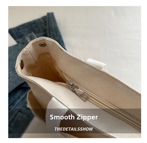 Detailed close-up of smooth metal zipper closure and canvas texture on tote bag