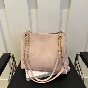 Pink minimalist tote bag with embossed letters and gold chain strap on a white background