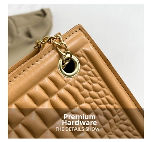 Detailed close-up of brown crocodile embossed leather texture with golden chain hardware