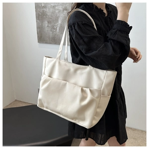 Détail du sac cabas en toile beige avec poche plissée élégante et texture souple