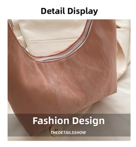 Detailed close-up of pink crescent handbag featuring shiny crinkled texture and silver zipper