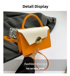 Detail view of stylish color-block handbag with orange leather and gold geometric clasp