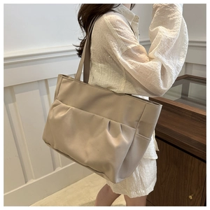 Détail d'un sac cabas beige en toile avec design plissé et doubles anses longues