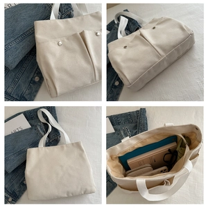Detail view of large cream canvas tote bag with front snap pockets and spacious interior