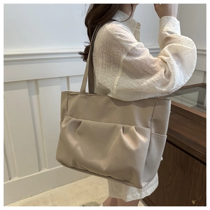 Détail du sac fourre-tout en toile beige avec poches plissées porté par un mannequin