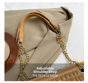 Detail of adjustable strap buckle and gold chain on brown quilted crossbody bag