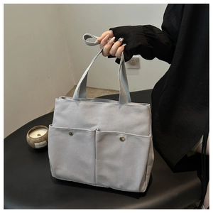 Gros plan d'un sac cabas en toile avec deux poches frontales et boutons-pression en métal