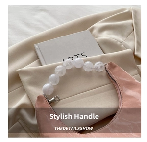 Detailed view of pink patent leather crescent bag with white acrylic beaded handle
