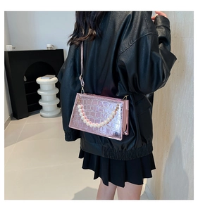Pink faux leather bag with pearl handle and crocodile texture worn by model