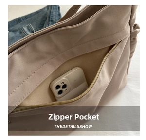 Detail view of functional side zipper pocket on a large canvas tote bag with phone inside