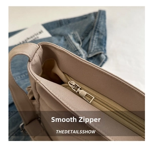 Detailed shot of a durable metal zipper on a soft khaki canvas bucket bag close-up