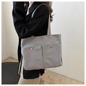 Détail du sac cabas en toile gris clair avec grandes poches avant et rivets argentés