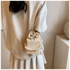 Detail of woven beige texture bag with pearl handle and golden chain strap
