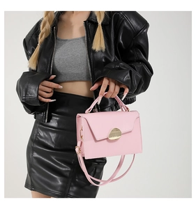 Pink glossy faux leather crossbody bag with a distinctive golden geometric buckle detail