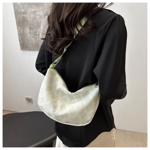 Close-up of light green hobo bag with woven texture worn by model in minimalist setting