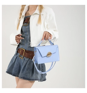 Detail of light blue structured handbag with golden pebble clasp and reinforced handles