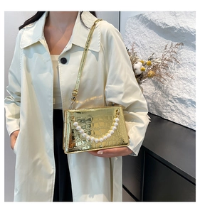 Detail of metallic gold crocodile embossed bag with elegant faux pearl handle and strap