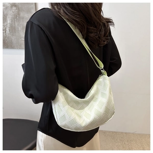 Detail view of mint green crescent bag with textured fabric worn by model