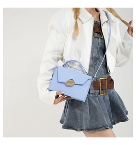 Detail of light blue structured crossbody bag with unique gold pebble metal buckle