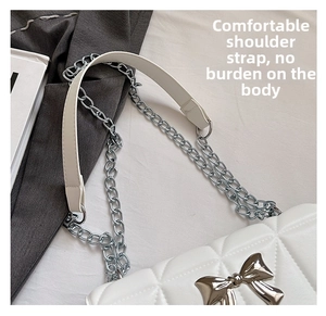 Détail du sac bandoulière blanc matelassé avec nœud argenté et bandoulière en chaîne