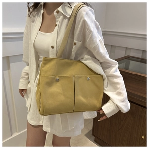 Sac fourre-tout en toile jaune gingembre avec poches avant porté par un mannequin