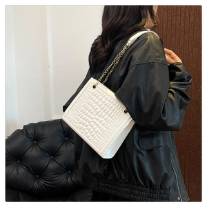 Detail of white crocodile embossed square bag with gold chain and metal eyelet accents
