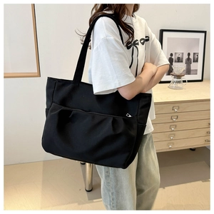Détail d'un grand sac cabas noir en toile avec poche plissée à l'avant pour le quotidien