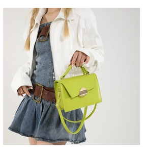 Detail of neon green structured handbag featuring a gold oval clasp and top handle