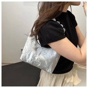 Detail of silver metallic pleated crescent bag with artistic texture and white ornament