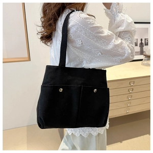 Détail d'un sac cabas en toile noire avec deux poches avant et boutons-pression