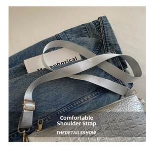 Detail showing silver crocodile-textured leather with grey nylon strap and gold hardware