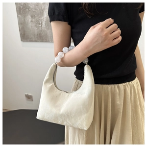 Close-up of minimalist crescent bag with marble texture and pearl handle worn on shoulder