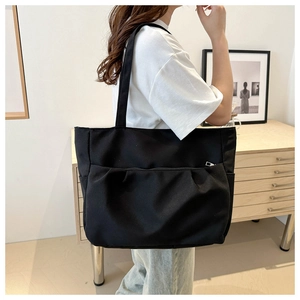 Détail d'un grand sac fourre-tout noir avec poche plissée avant et fermeture éclair fluide