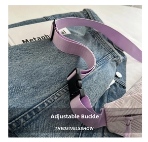 Detalle de correa tejida morado claro con hebilla ajustable de plástico negro en denim