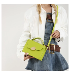 Lime green leather handbag with a unique metal buckle and adjustable shoulder strap detail