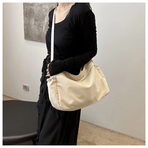Detail view of large cream canvas bucket bag with soft texture and side pleats