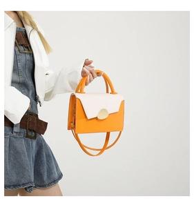 Détail du sac à bandoulière bicolore orange et blanc avec fermoir doré et poignées