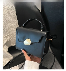 Detail of black faux leather handbag with oval metal clasp and elegant handle